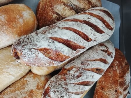 Close-up of rustic flour-dusted baguettes with diagonal slashes in a pile of artisanal bread