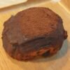 Chocolate pastry coated in cocoa powder on a wooden board or table surface
