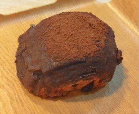 Chocolate pastry coated in cocoa powder on a wooden board or table surface